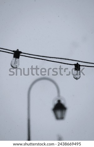 Two lightbulbs hanging over the street with a street lantern in the background. Raindrops falling down the lightbulbs. Photo taken in Les 3 vallées, Val Thorens, Les Belleville, France.  