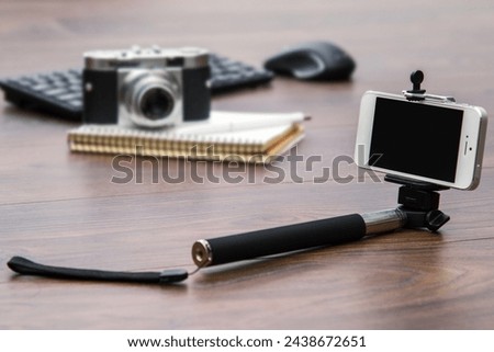 Selfie stick and smart phone and blurred retro camera