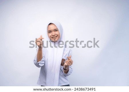 Female Indonesian high school student in white and grey uniform showing love korea sign with finger at Copy Space Advertising Your Text, Standing Isolated Over white Studio Background