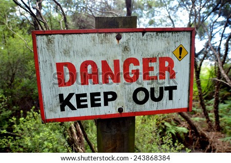 Danger keep out wooden sign panel posted in the wilderness of New Zealand. Concept photo of travel and recreational leisure outdoor activity. No people. Copy space