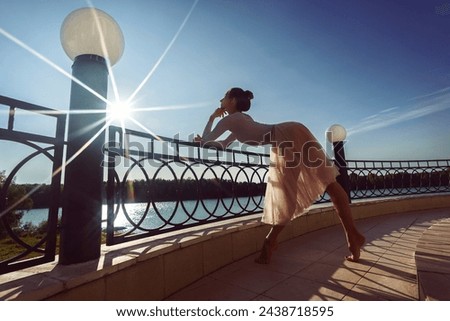 A ballerina in chopin with beautiful feet walks barefoot by the terrace fence on a summer day