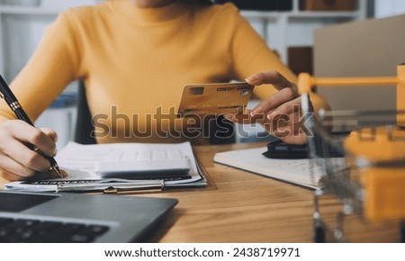 Young woman holding a smartphone, tablet showing payment success and credit card with yellow parcel box as online shopping concept in office Royalty-Free Stock Photo #2438719971