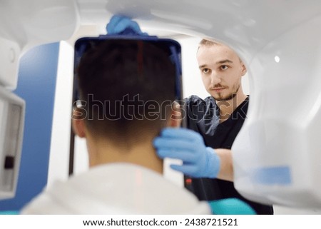 Doctor dentist are going to do a digital x-ray with man patient in dentistry clinic. Panoramic radiography. Modern professional dental equipment for hospital, clinic, medical center. Royalty-Free Stock Photo #2438721521