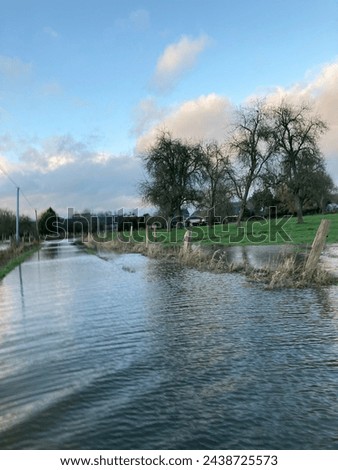 Exterio visual photo view of a flooding river over the fields in the countryside of France n Normady with the fresh water covering all over the natural nature farm and road with trees and herbs plants