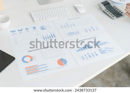 An array of business reports and marketing analysis charts are spread out on a desk, depicting various data visualization for strategic planning