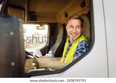 Truck driver job. Logistics - proud driver or forwarder on truck and trailer, on a transshipment point. Transportation service. Royalty-Free Stock Photo #2438745791