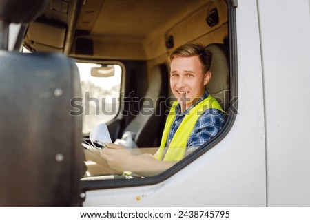Truck driver job. Logistics - proud driver or forwarder on truck and trailer, on a transshipment point. Transportation service. Royalty-Free Stock Photo #2438745795