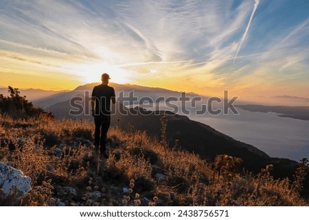 Hiker man with scenic sunrise view from top of mount Kula near Omis, Dinara mountains, Split-Dalmatia, Croatia, Europe. Coastline of Makarska Riviera, Adriatic Sea. Balkans in summer. Biokovo mountain Royalty-Free Stock Photo #2438756571