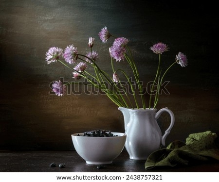 Modern still life with a bouquet of blooming onions and honeysuckle on a dark background.