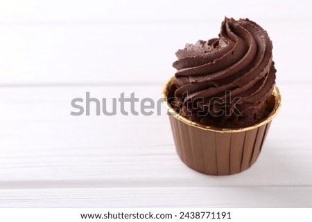Delicious chocolate cupcake on white wooden table, closeup. Space for text