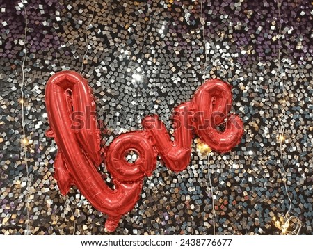 A closeup picture of letters LOVE in red colored ballons against a glittering background.