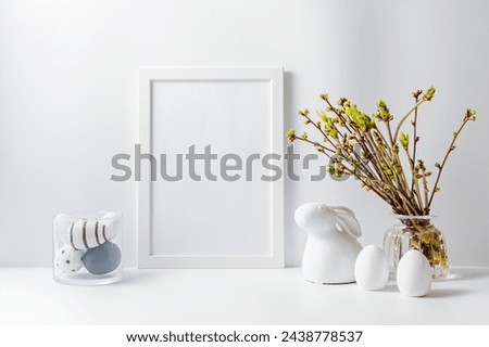 Home interior with easter decor. Mockup with a white frame and green buds on branches in a vase on a light background