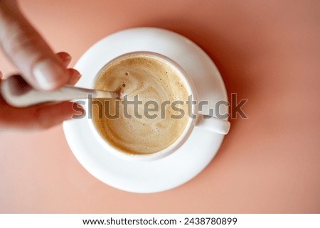 Top view of unrecognizable person dissolving sugar with spoon in cup of coffee