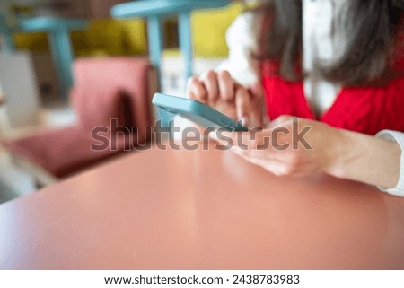Closeup shot of an unrecognizable woman using a cellphone in a cafe