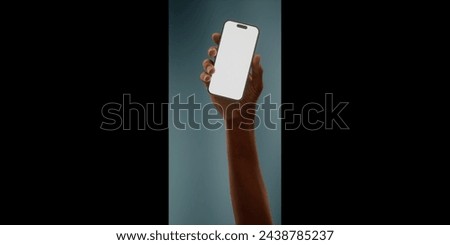 Black African-American hand displays a modern smartphone with a blank screen against a deep teal background, ideal for presenting apps or mobile interfaces in a clean and contemporary setting Royalty-Free Stock Photo #2438785237