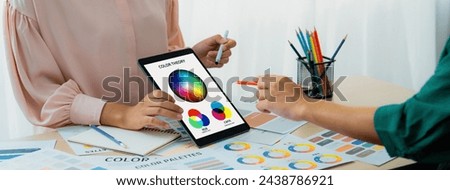 A cropped picture of professional designer selects the color by using color theory and comparing with color wheel on table with designing material and equipment scatter around. Variegated. Royalty-Free Stock Photo #2438786921