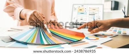 Cropped image of interior designer chooses color from color swatches while laptop displayed website wireframe designs for mobiles app and website. Creative design and business concept. Variegated.
