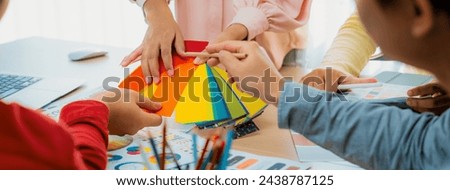 Cropped image of professional designer pick up the color at meeting at meeting table with color palette and document scatter around. Creative design and teamwork concept. Closeup. Variegated.