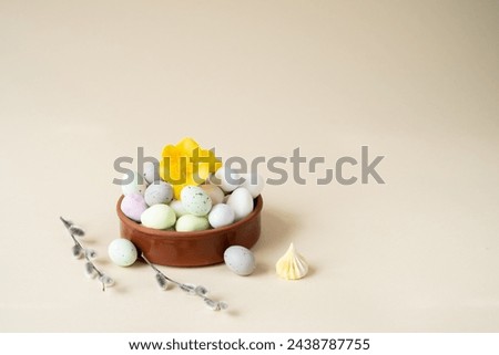 plate with sweet dessert in the form of Easter eggs and a sprig of mimosa on a beige background