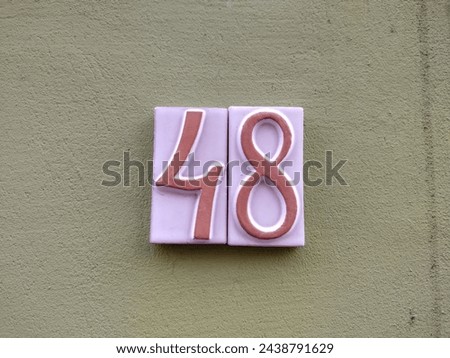 Decorative ceramic sign indicating street number forty-eight on a wall.