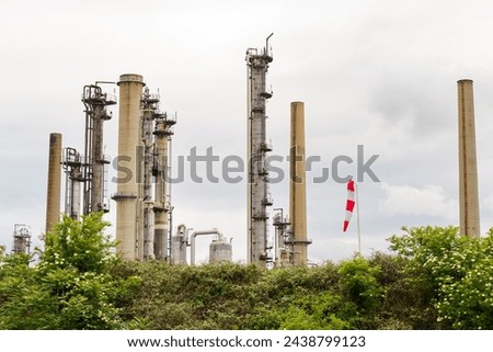 A row of tall, disused industrial smokestacks stands against a cloudy sky, remnants of a bygone manufacturing era, showcased here in a quiet state of neglect. Royalty-Free Stock Photo #2438799123