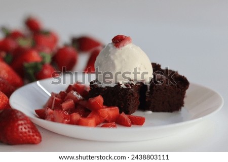 Chocolate brownie with fresh strawberries and a scoop of creamy vanilla ice cream, perfect for dessert menus and sweet cravings. Featuring Egg less preparation of brownie. Shot on white background Royalty-Free Stock Photo #2438803111