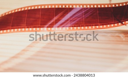 35mm photographic film, color negative film on wooden table background.Vintage equipment for old filmmaking, Movie production, Entertainment industry concept.