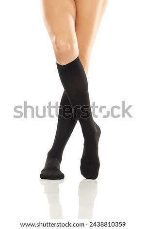 Female legs in compression Hosiery. Medical stockings, tights, socks, calves and sleeves for varicose veins and venouse therapy. Clinical knits. Sock for sports isolated on white studio background Royalty-Free Stock Photo #2438810359