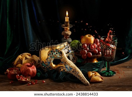 Multicolor carnival mask, wine, burning candle on a dark wooden table. Purim, Mardi Gras holiday concept. Rustic.