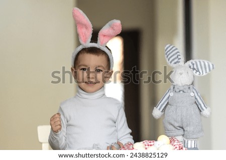 Funny little boy playing with Easter eggs. Preparation for the celebration of Easter. A boy with bunny ears is preparing for Easter.