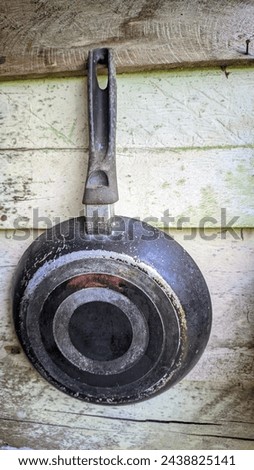 a picture of an old rusty pan hangs on the plank wall