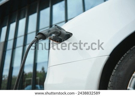 Close up of the Hybrid car electric charger station with power supply plugged into an electric car being charged