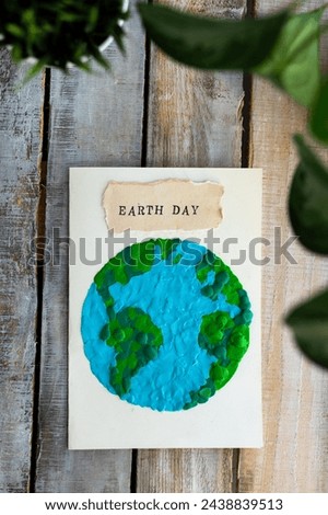 Children's craft for the Earth Day celebration. Little boy holding handmade simple postcard with a picture of our Planet made of plasticine. Concept of environment education for kids in kindergarten 