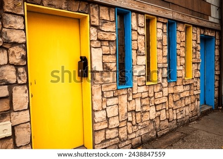A charming stone house featuring striking blue and yellow doors and windows, evoking the vibrant hues of the flags of Sweden and Ukraine.