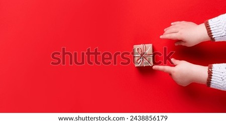 Baby hands holding gift box on red background. template, banner, christmas concept, copy space.