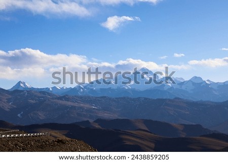 Iconic peaks of Mt. Everest, Lhotse, and Makalu stand tall against the Tibetan sky, viewed from Pang La Pass, with a glimpse of the road leading to Everest Base Camp.