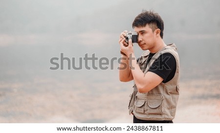 Young man with a vintage camera captures the beauty of the outdoors on a hazy day.