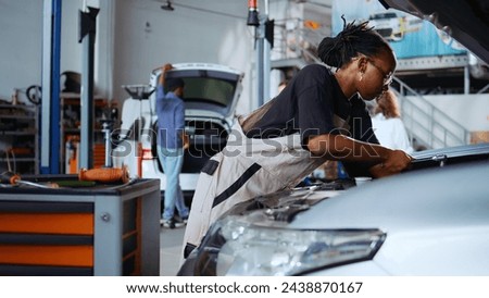 Meticulous employee in repair shop using torque wrench to tighten screws after checking car parameters during maintenance. Expert using professional tool in garage to mend vehicle, dolly out shot Royalty-Free Stock Photo #2438870167