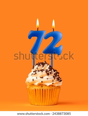 Blue birthday candle and cupcake - Number 72 Royalty-Free Stock Photo #2438873085