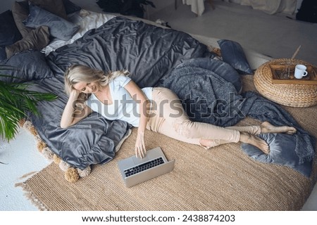 Happy beautiful blonde woman working, making video call, watching movie on a laptop in cozy home bedroom modern interior. Home quarantine Covid-19 pandemic Corona virus. Remote work from home concept. Royalty-Free Stock Photo #2438874203