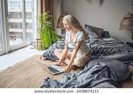 Happy beautiful blonde woman working, making video call, watching movie on a laptop in cozy home bedroom modern interior. Home quarantine Covid-19 pandemic Corona virus. Remote work from home concept. Royalty-Free Stock Photo #2438874215
