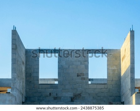 Window openings on top level of the concrete shell of a two-story single-family dwelling under construction in a suburban residential development on a sunny morning in southwest Florida