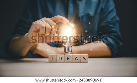 Innovative technology in science and communication concept. hand touching on light bulb on wood block with Word Ideas, new idea concept with innovation and inspiration. Royalty-Free Stock Photo #2438890691