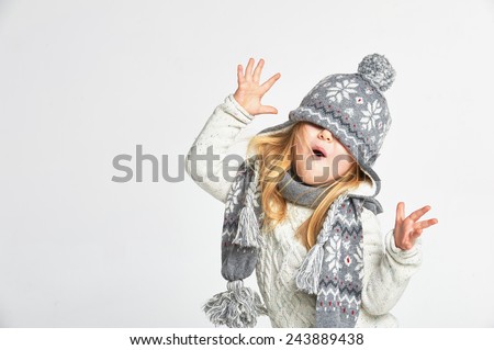 Beautiful blond girl playing in the winter warm hat and scarf on a white background