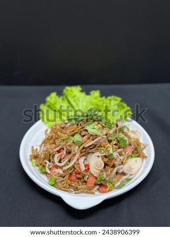 A picture of a plate of thailand food kerabu ikan bilis with black background