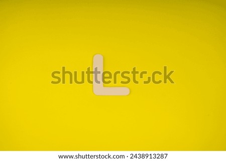Letter L in wood on yellow background Royalty-Free Stock Photo #2438913287