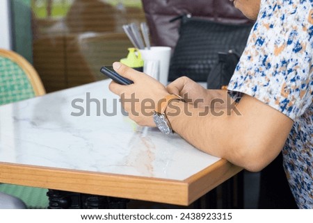 Young Man Holding Mobile Phone in Restaurant
