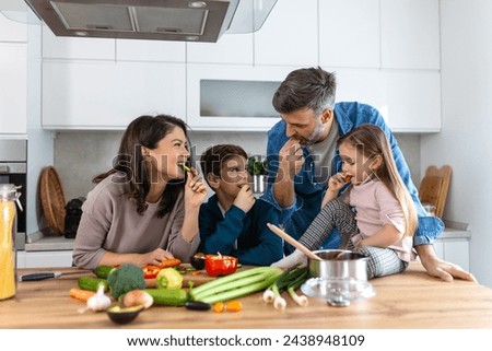 Overjoyed young family with son and daughter have fun cooking diner or lunch at home together, happy smiling parents enjoy weekend play with small children doing cooking in kitchen