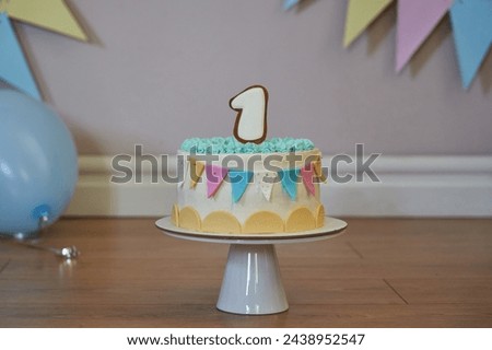 birthday cake with a big number one and garlands on the wall made of flags. first birthday cake