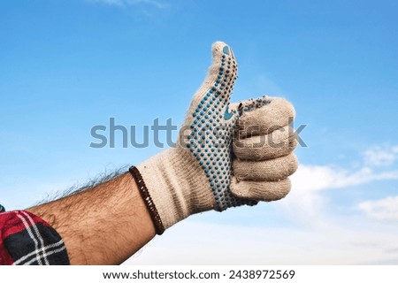 Gardener wearing gardening gloves gesturing thumbs up as a recommendation and approval hand sign, selective focus